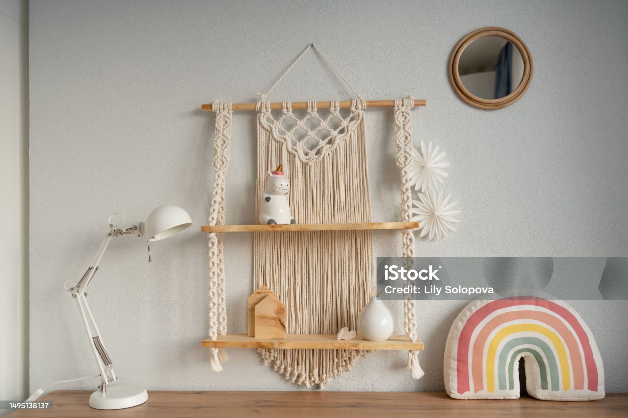 A large wooden macrame shelf hangs on the wall. Beautiful home children room interior.